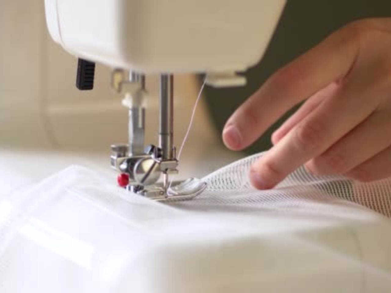 Cusătură manuală detaliată pe o draperie elegantă, realizată cu precizie într-un atelier, simbolizând calitate, grijă și pasiune pentru frumos