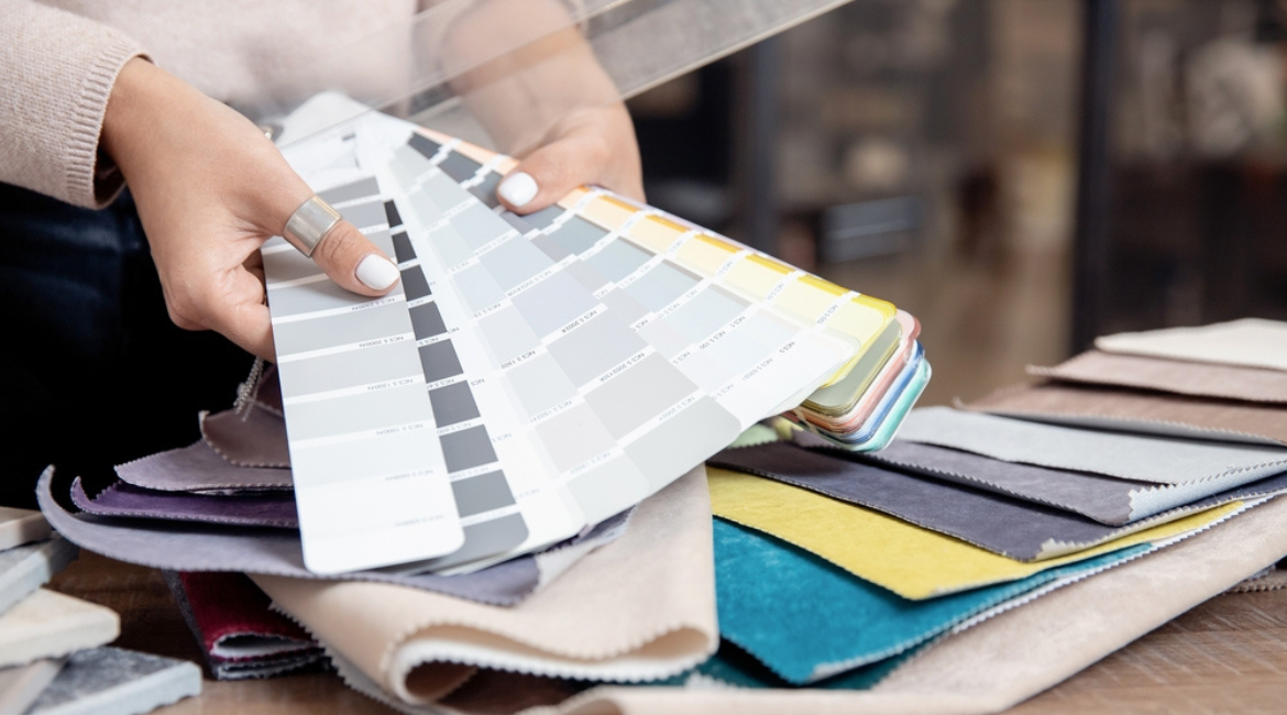 Consultant Grand Textil prezentând mostre de materiale într-un living modern, alături de clientul care analizează și alege draperii personalizate